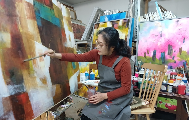 류일지 작가가 작업실에서 ‘축제–유희’ 시리즈 신작을 제작하고 있는 모습. 따뜻한 색감과 감성적 추상을 특징으로 하는 작가의 작품 세계는 자연과 인간의 조화, 그리고 삶의 유희를 회화적으로 표현한다. (사진제공 = 류일지 작가)