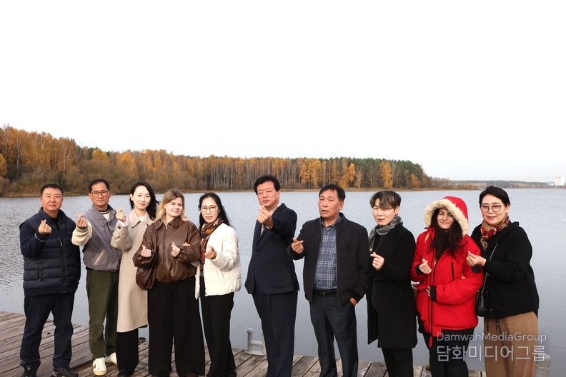 자슬라브스코예 호수(‘민스크 바다’)의 선착장에서 한국 대표단이 따뜻한 손하트 인사를 전하고 있다. 뒤로 펼쳐진 편백나무 숲이 황금빛 단풍으로 물들어, 호수의 잔잔한 수면과 어우러진 풍경이 마치 한 폭의 수채화를 닮았다. 늦가을 햇살 아래, 사람들의 미소와 자연의 빛이 함께 어우러진 순간이 벨라루스의 평화로움을 전한다.